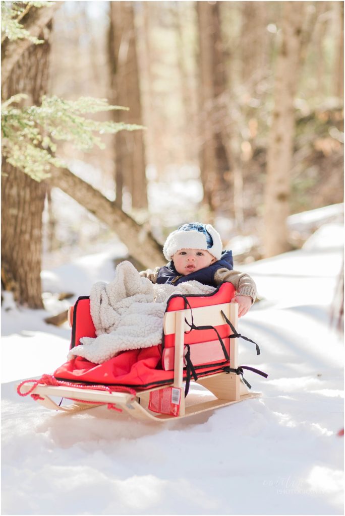 Baby in red sled winter time 