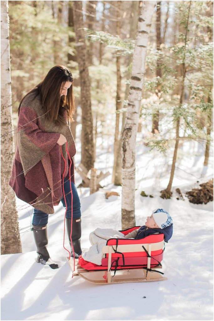 Mom pulling baby in sled winter time