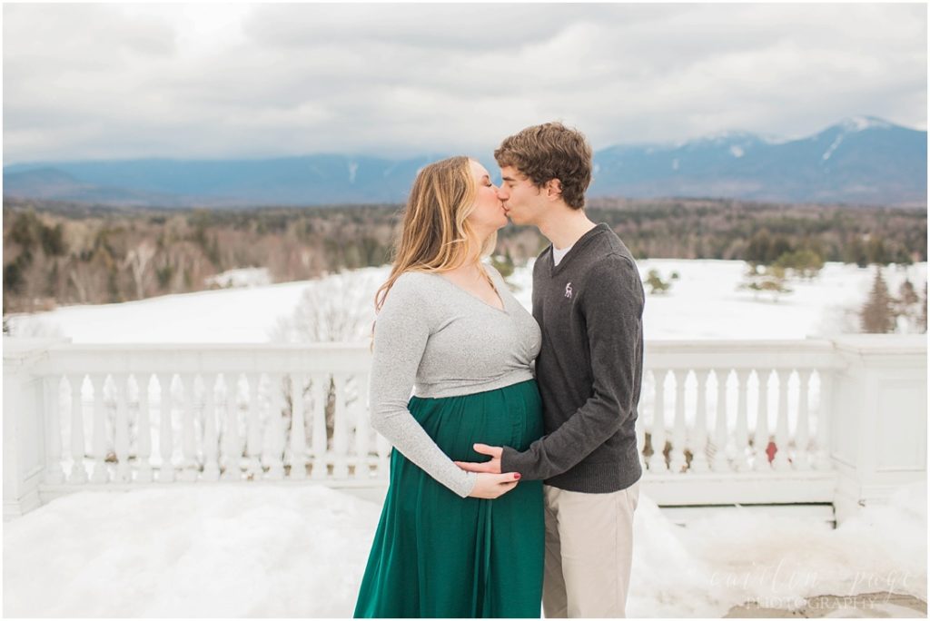 Man and pregnant woman kissing in front of mountains