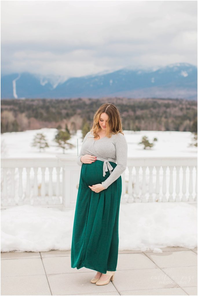 Pregnant woman in green skirt in front of mountains 