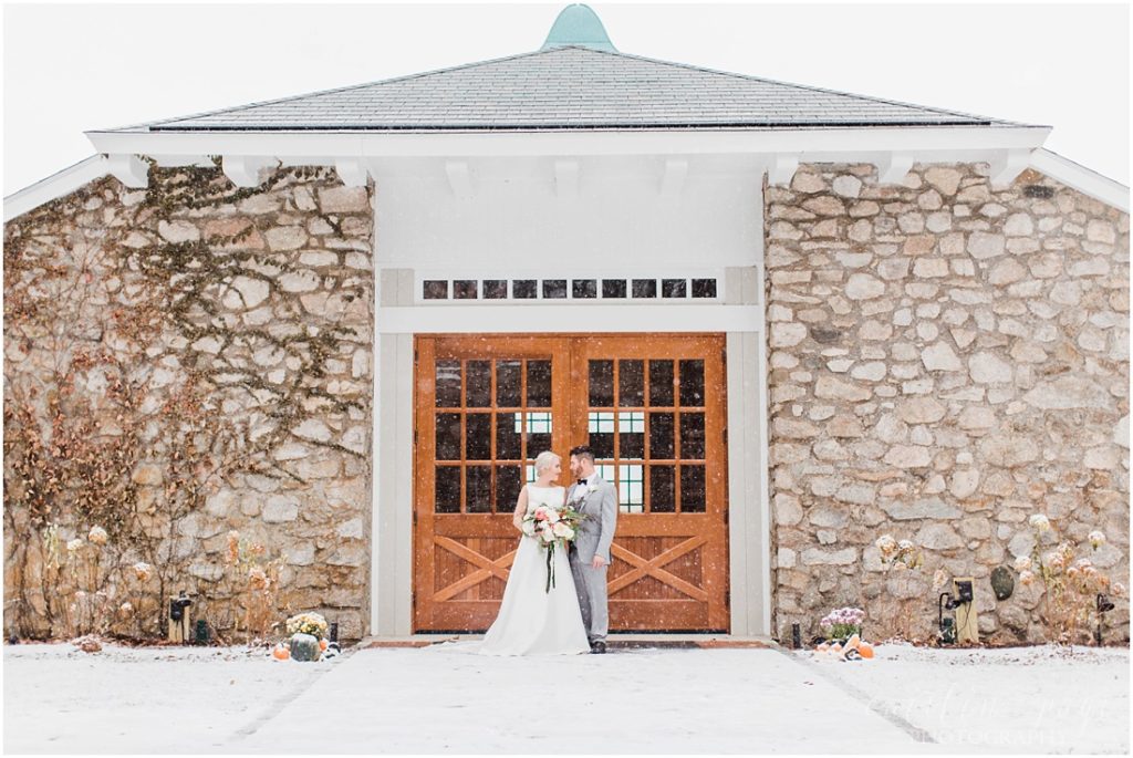 bride-and-groom-outdoor-winter-portraits-in-front-of-stone-barn-snowstorm