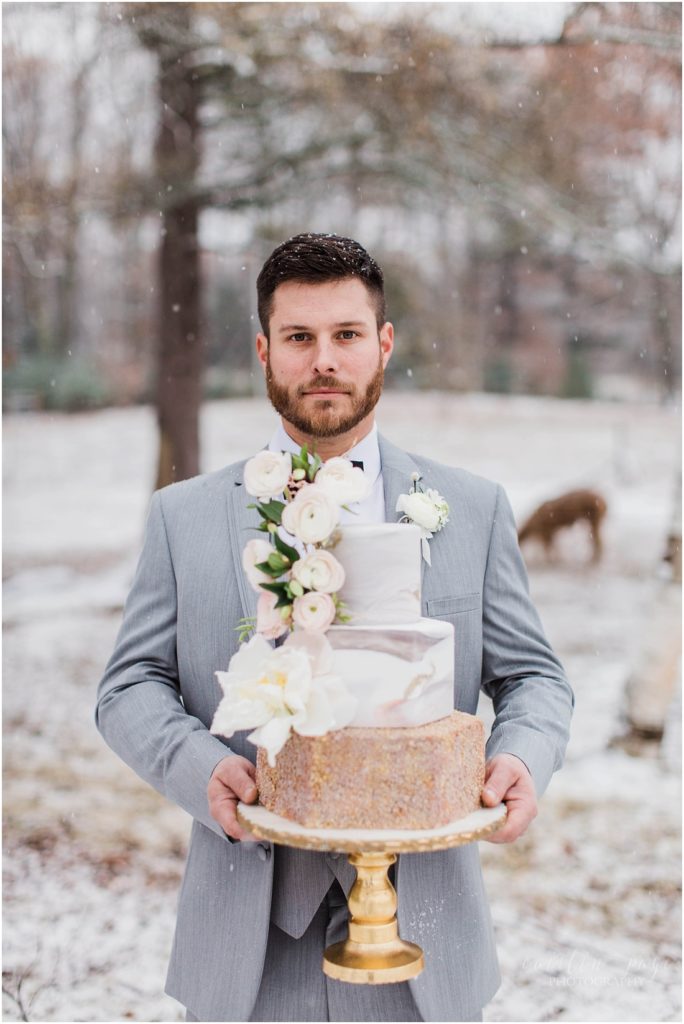 groom-holding-wedding-cake-in-snow
