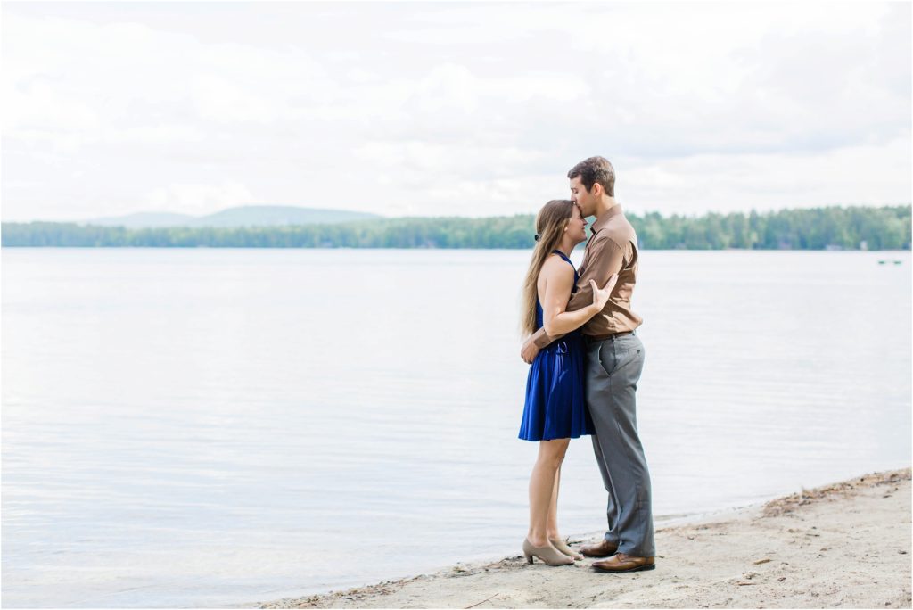 man kissing woman's forehead by the water