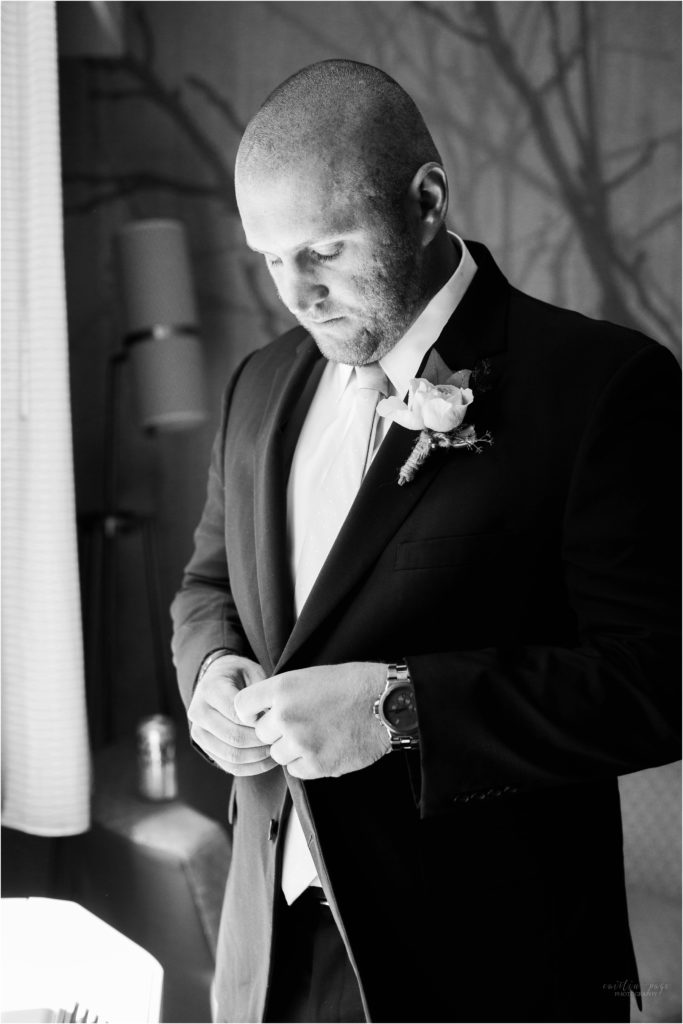 groom buttoning suit black and white portrait