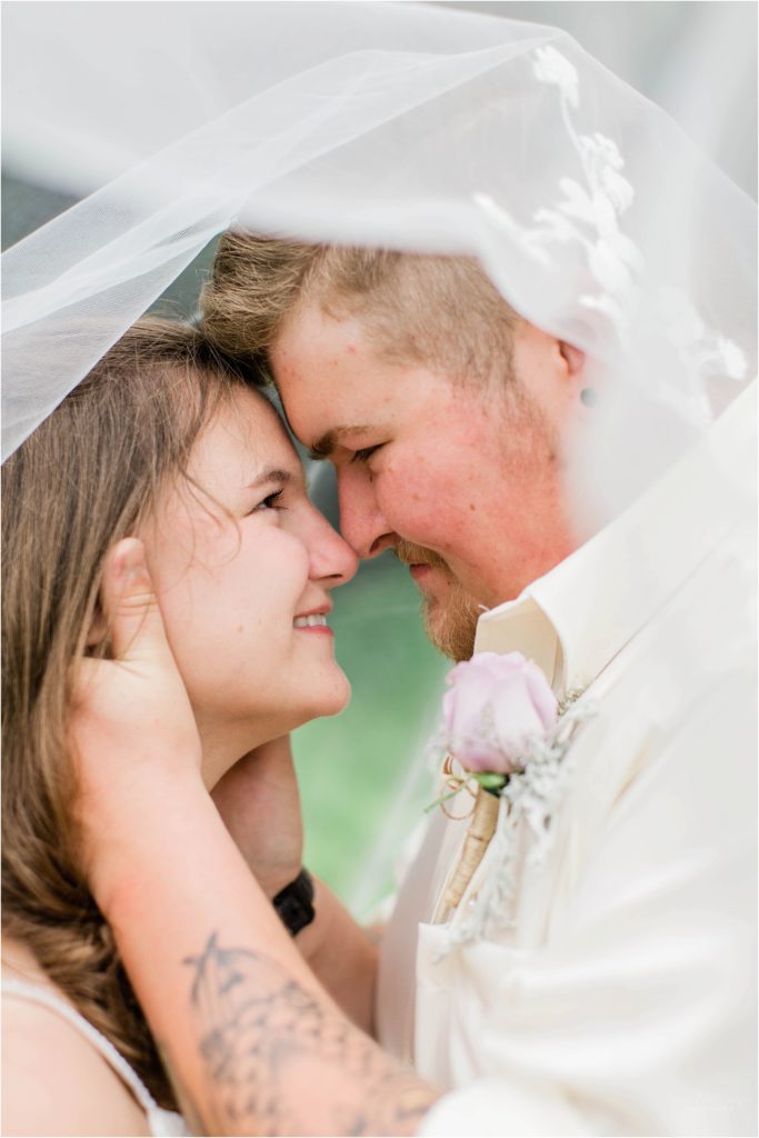 bride and groom together under wedding veil
