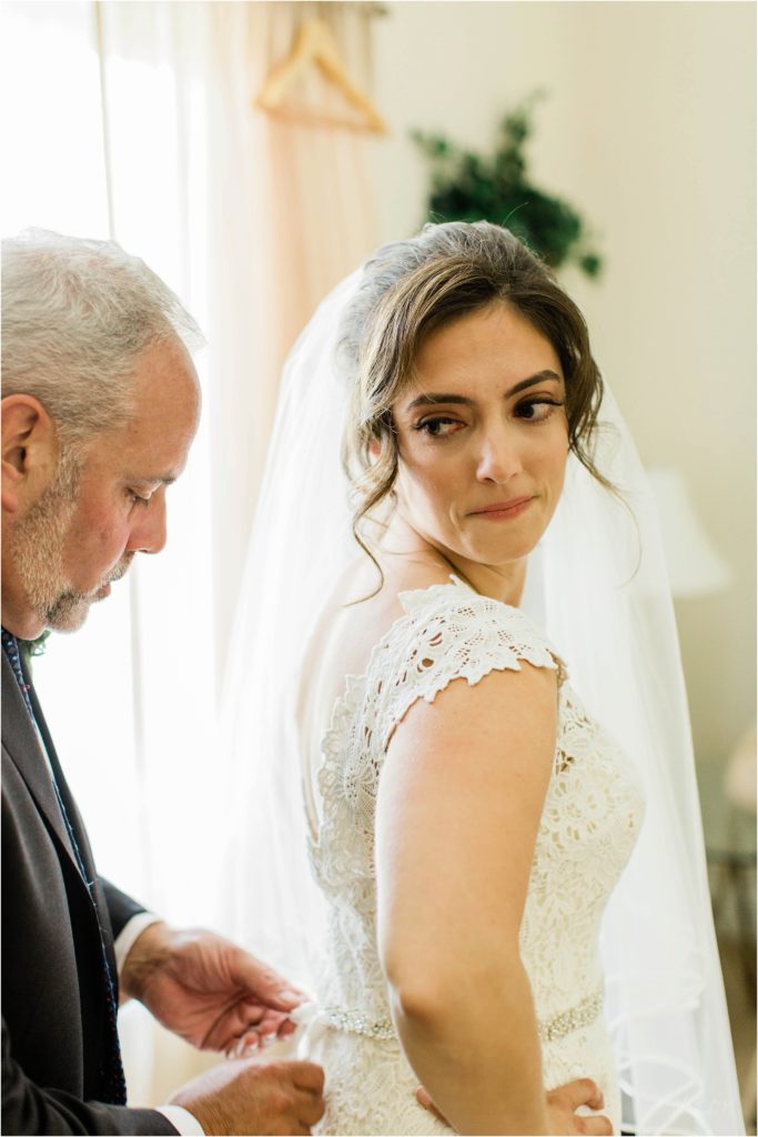 father of bride tying bow on wedding dress