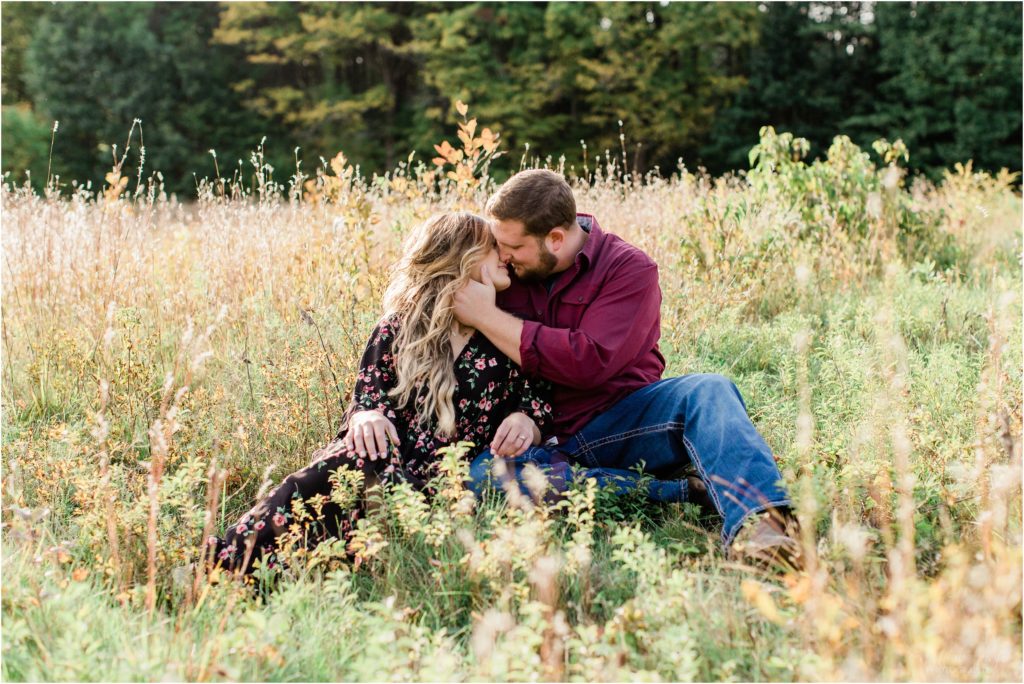 couple looking at each other while sitting in a field engagement session