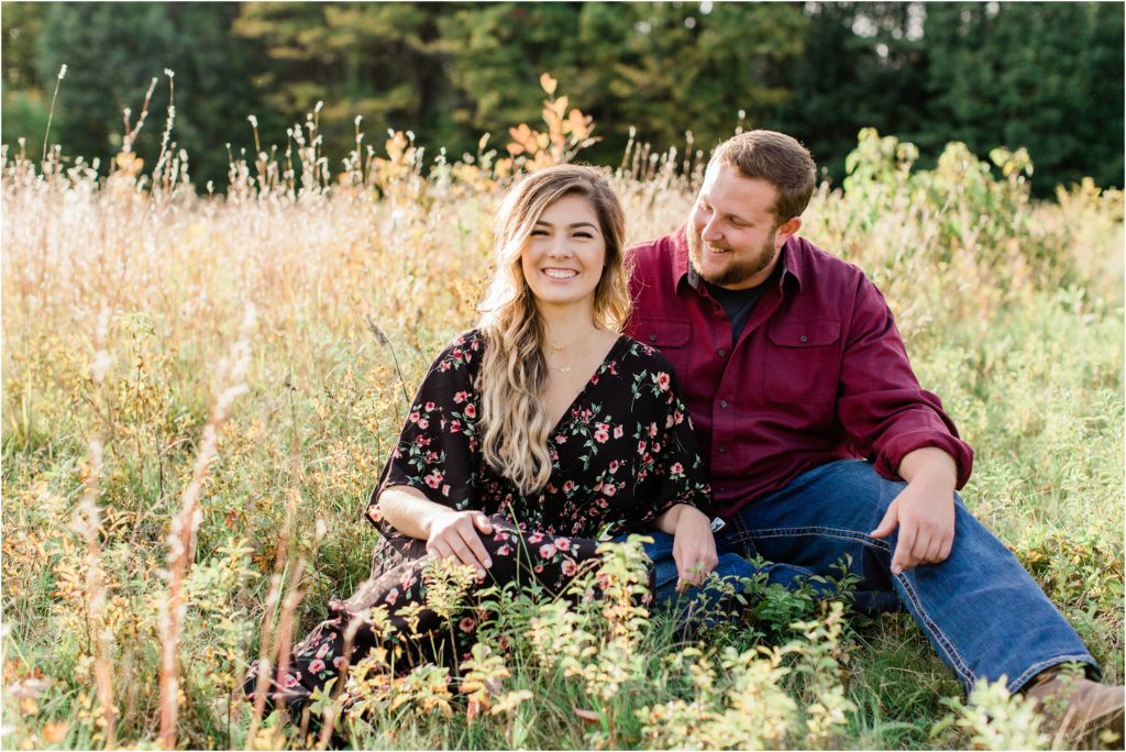 couple laughing sitting in field engagement session fall new hampshire