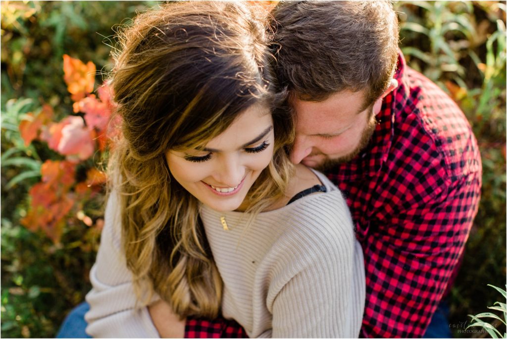 couple snuggled together in field new hampshire engagement session