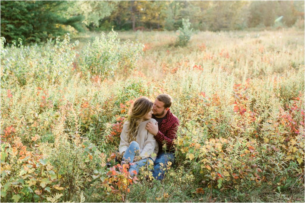 couple sitting together in field effingham engagement session