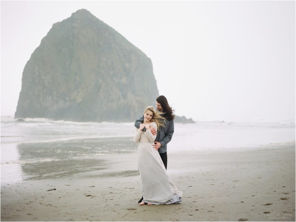 couple standing in front of rock cannon beach oregon