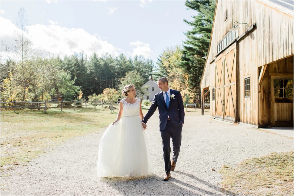 bride and groom walking by barn