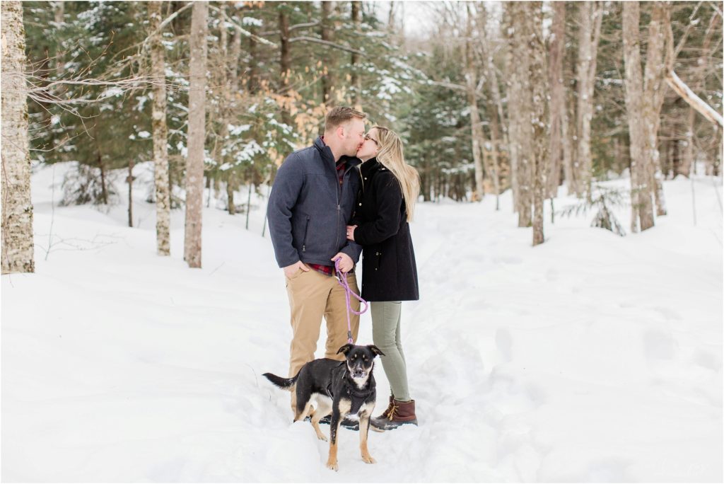 couple kissing in snow with dog