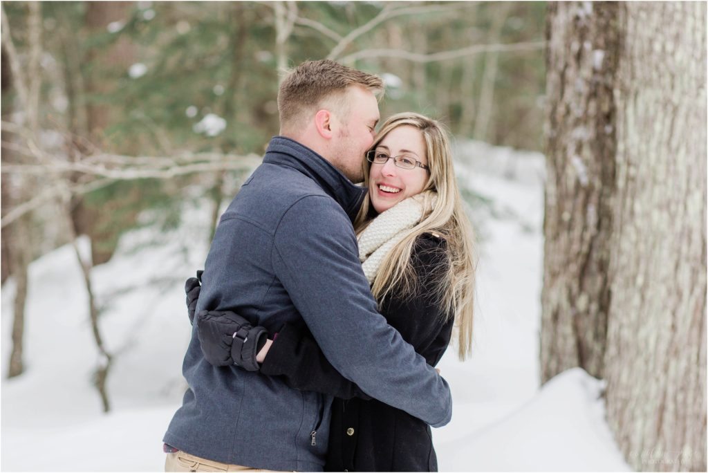 man kissing woman head snow