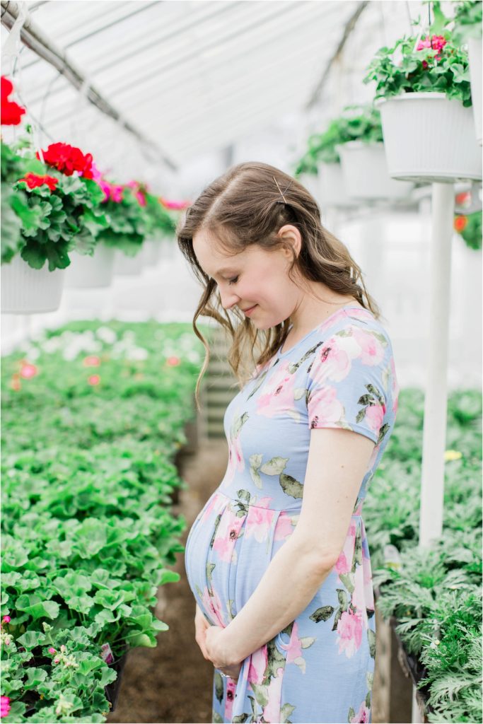 pregnant woman looking at belly in plant nursery