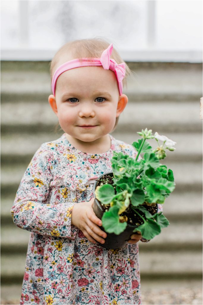 toddler girl holding onto potted flower