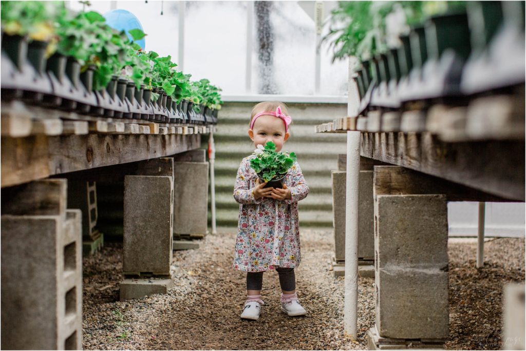 little girl standing in plant nursery aisle