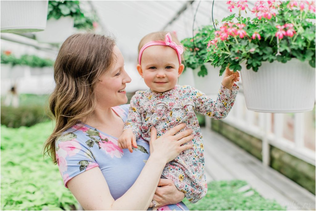 mom and toddler girl looking at pink flowers