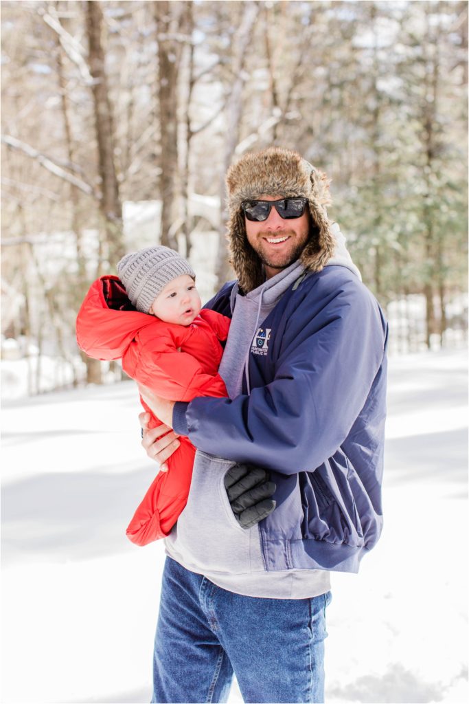 man holding baby in red snow suit