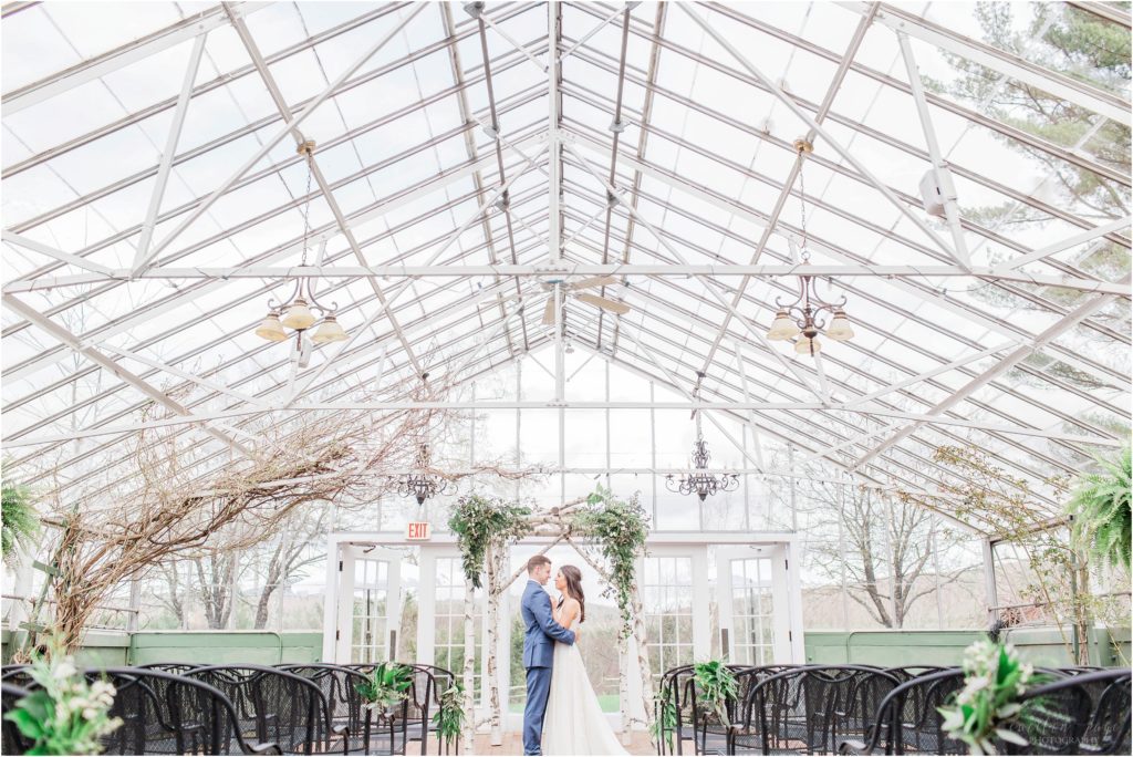 bride and groom standing together in greenhouse