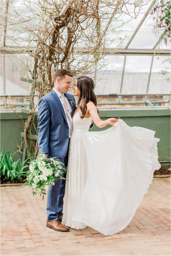 bride and groom standing together in greenhouse