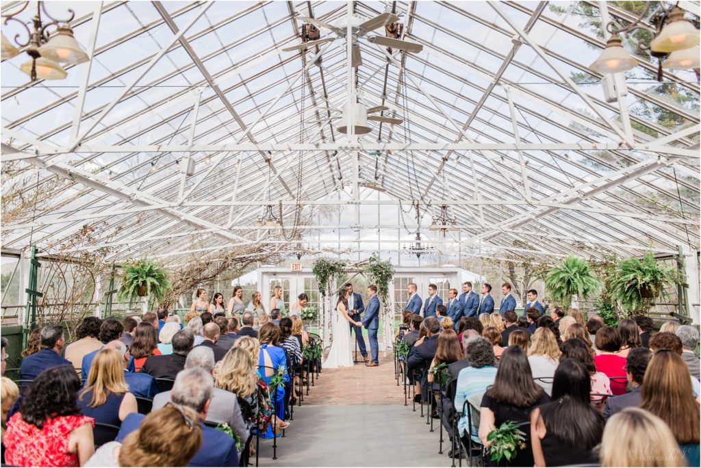 bride and groom standing under birch arbor in greenhouse