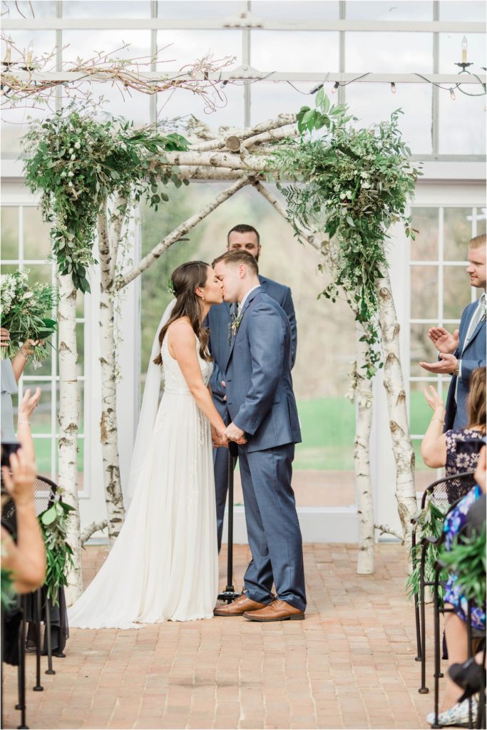 bride and groom kissing under arbor