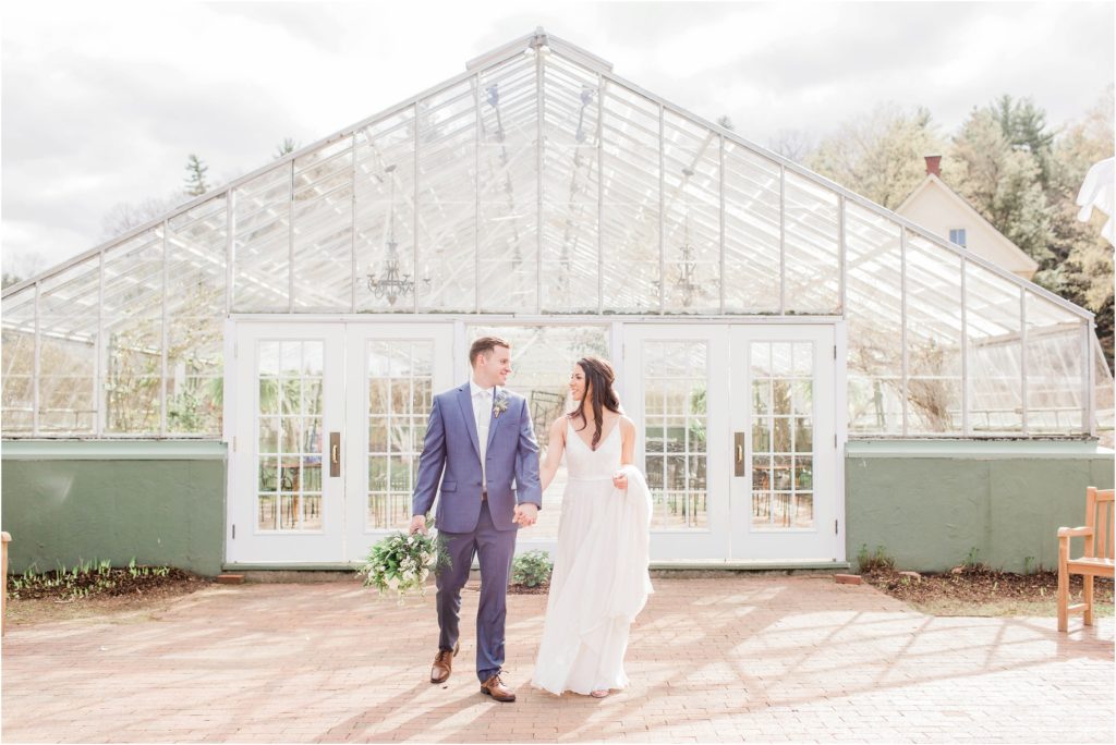 bride and groom walking in front of greenhouse
