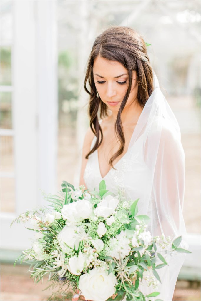 bride holding bouquet in front of greenhouse