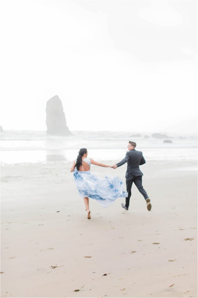 Bride and groom running together on Cannon Beach