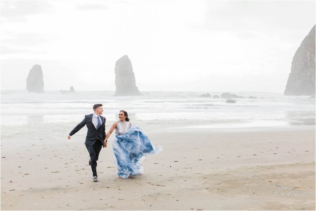 Bride and groom running together on Cannon Beach