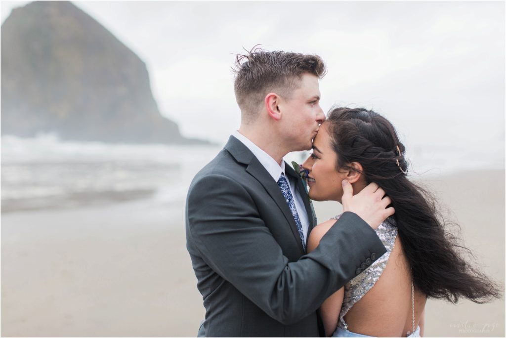 Groom kissing bride on the forehead on Cannon Beach in Oregon