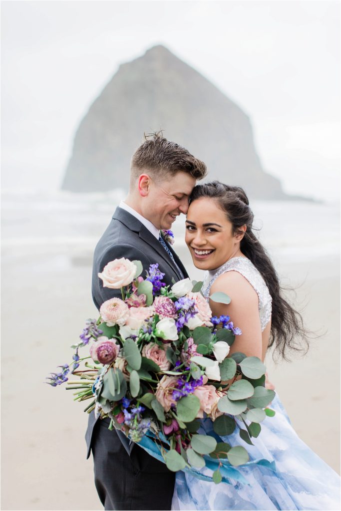 Couple snuggled together on Cannon Beach at styled elopement