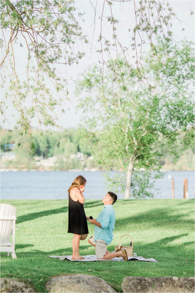man proposing to woman by lake winnipesaukee