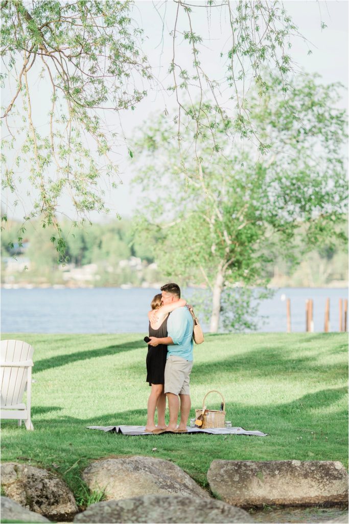 man and woman hugging by lake winnipesaukee