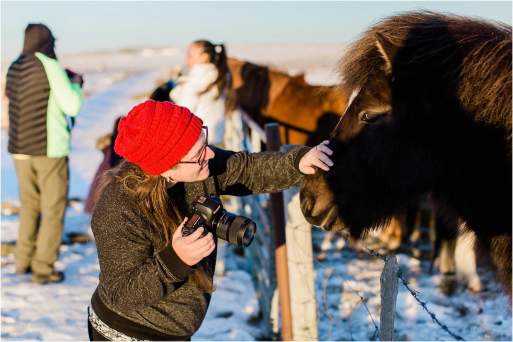 woman in red hat petting icelandic pony