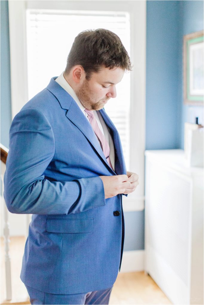 groom buttoning blue suit