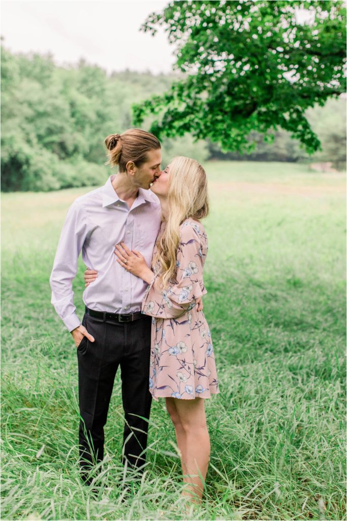 Man and woman kissing in field under large maple tree