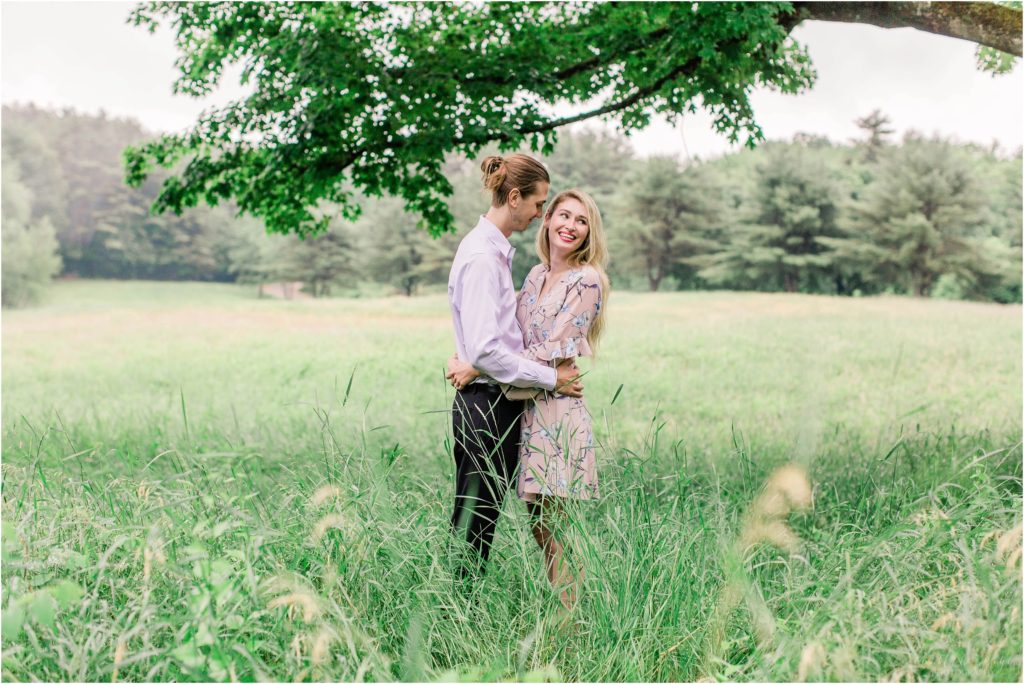 Man and woman standing in field holding each other