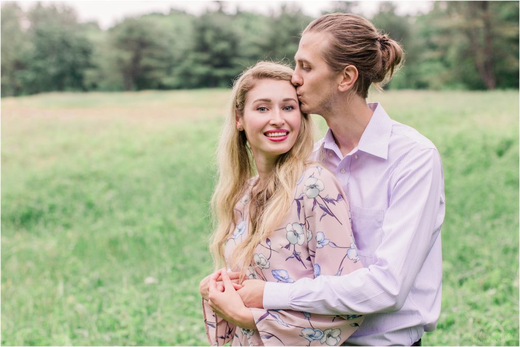 Man snuggling woman in large field