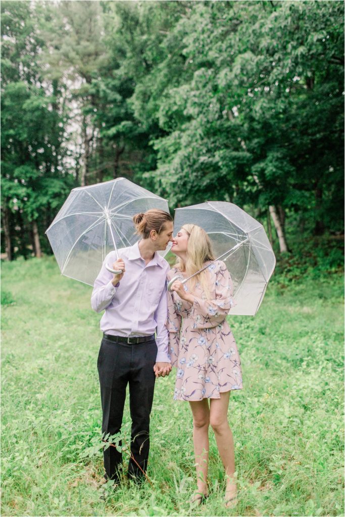 Man and woman kissing in field with clear umbrellas