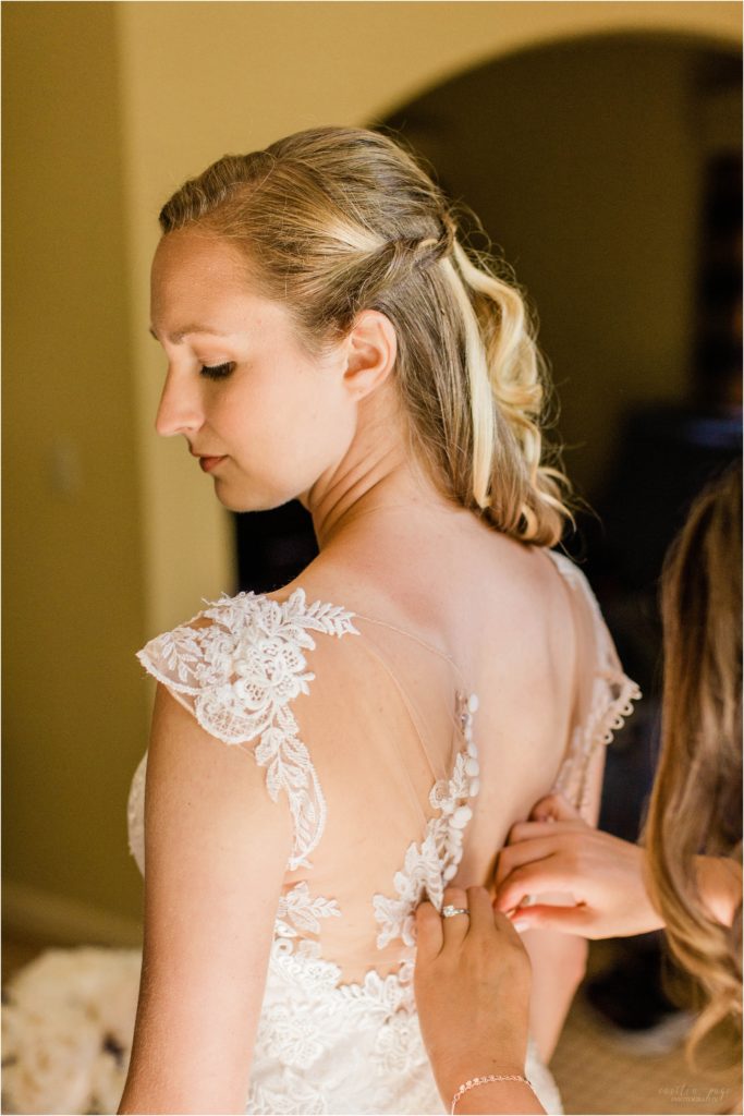 bride getting buttoned into her dress