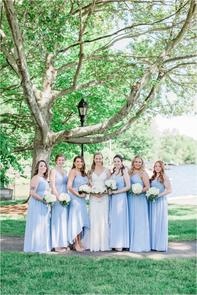 bridesmaids standing in front lake