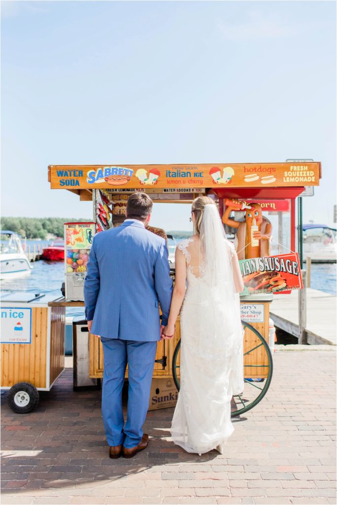 bride and groom standing in front of hot dog cart