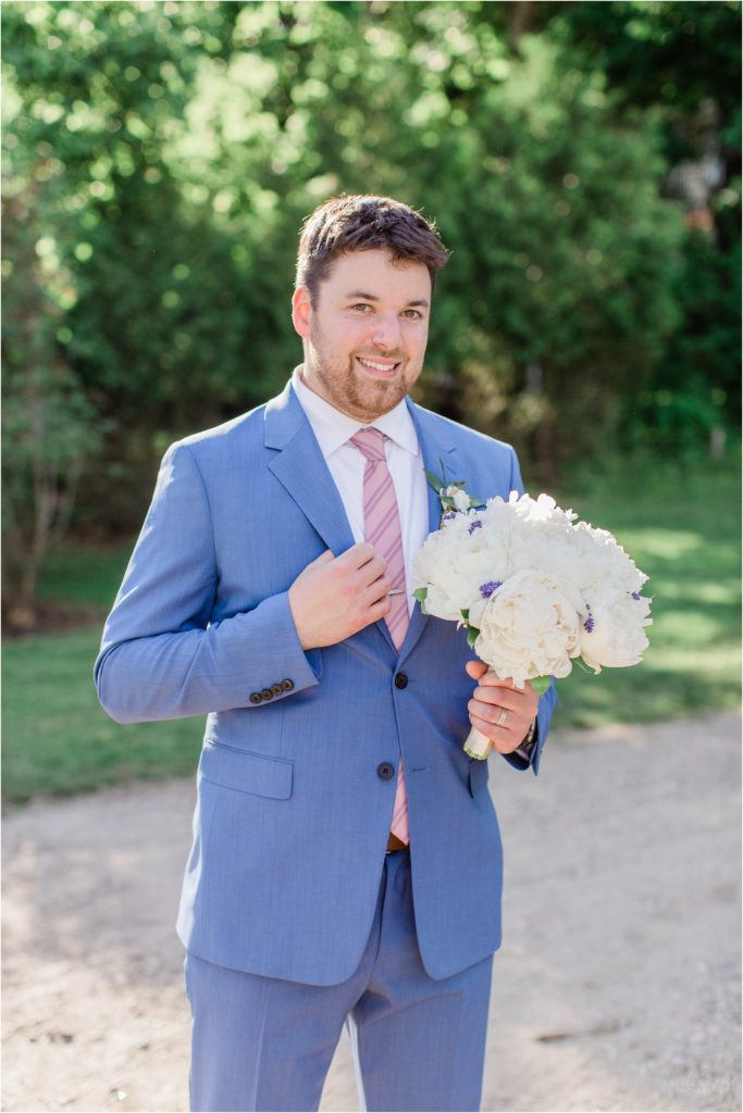 groom standing holding wedding bouquet