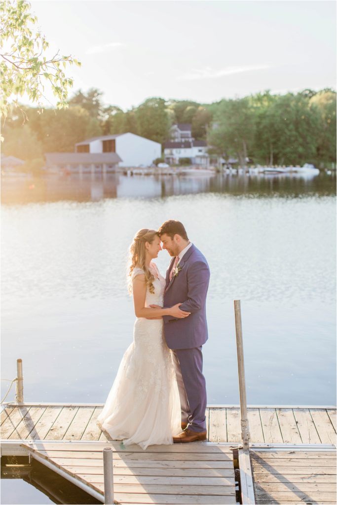 bride and groom standing on dock at sunset