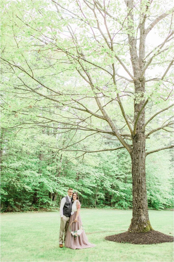 bride and groom standing under tree