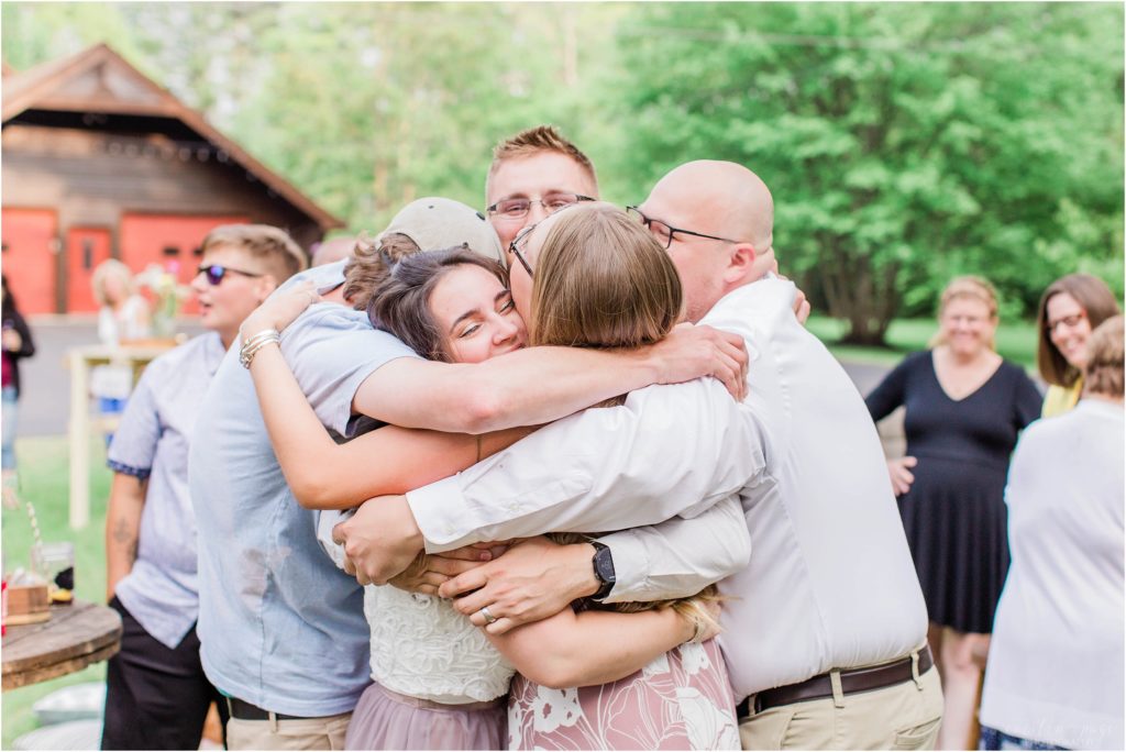 best man and maid of honor hugging bride and groom