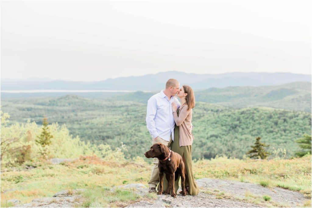 couple standing on mountain with dog
