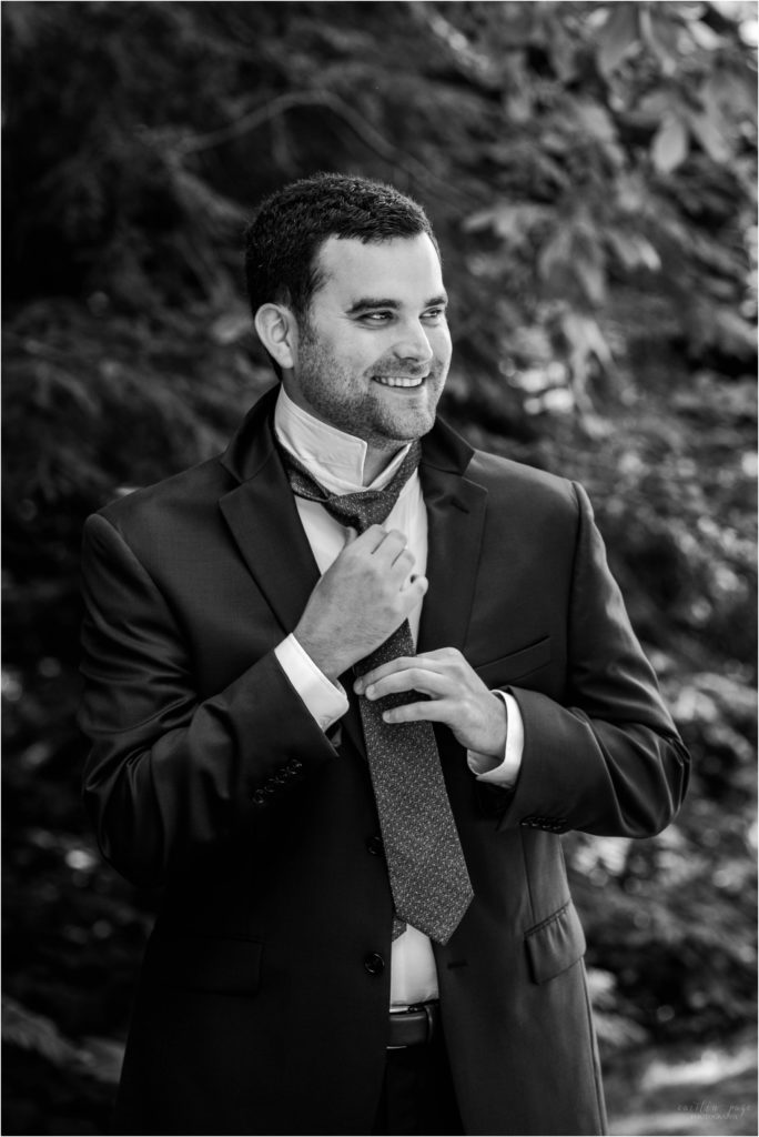 Black and white portrait of man tying tie